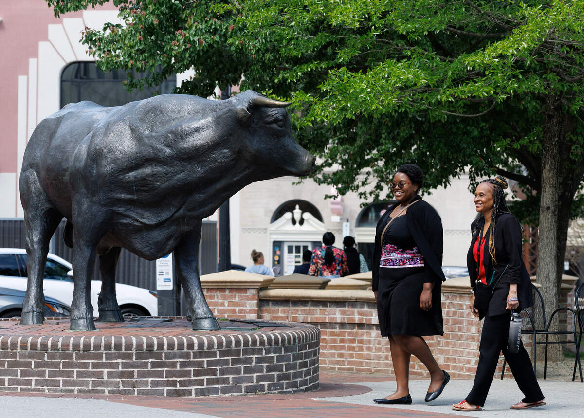 People walk by the Major the Bull sculpture on Wednesday, April 16, 2025, in Durham, N.C.