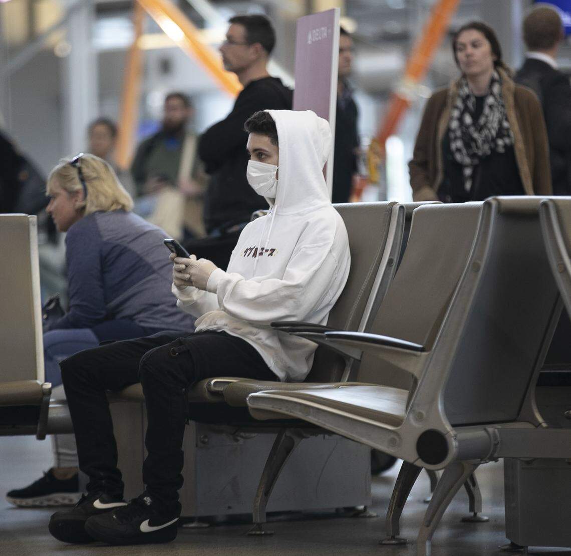 Collin Flynn, a student at UNC-Chapel Hill, waits for for two friends to arrive on an international flight inside Terminal 2 on Wednesday, March 4, 2020 at RDU International Airport in Morrisville, N.C. Flynn said the reported possible case of the COVID-19 virus in Wake County prompted him to wear a protective mask and gloves when he visited the airport.