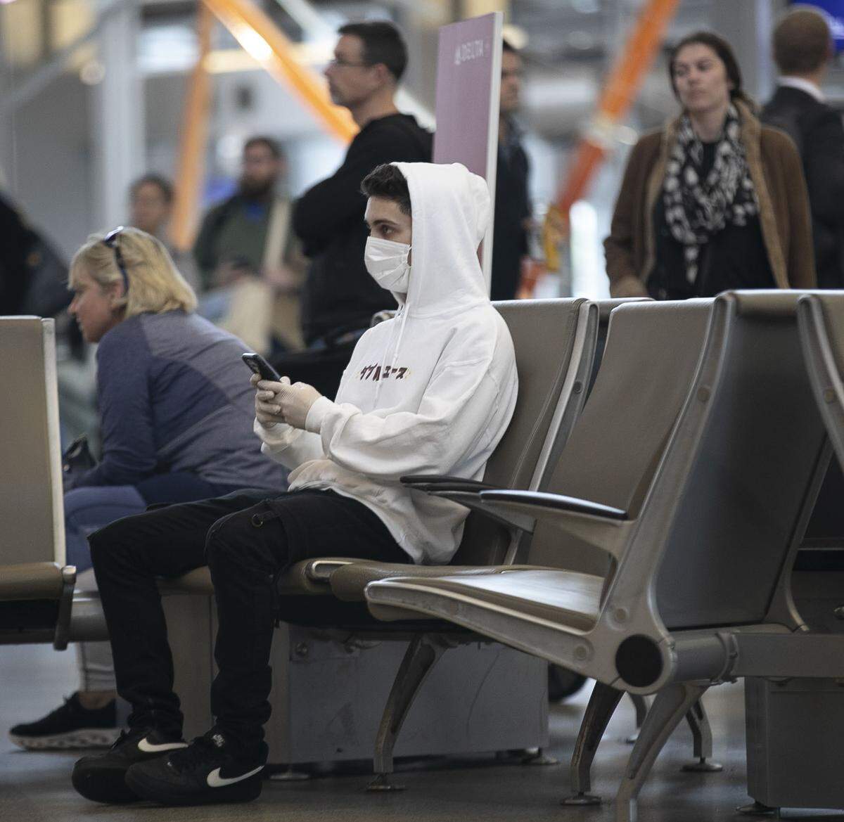 Collin Flynn, a student at UNC-Chapel Hill, waits for for two friends to arrive on an international flight inside Terminal 2 on Wednesday, March 4, 2020 at RDU International Airport in Morrisville, N.C. Flynn said the reported possible case of the COVID-19 virus in Wake County prompted him to wear a protective mask and gloves when he visited the airport.