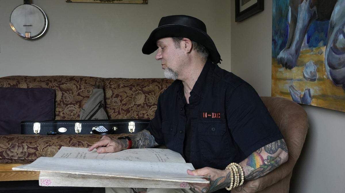 Robert Veeder, addiction specialist, looks over a large book filled with handwritten passages in his office in Fairport Tuesday, May 13, 2025. Veeder runs A Better High Personalized Addiction Recovery Services. The book is filled with passages from other addicts that have been apart of group sessions with Veeder.