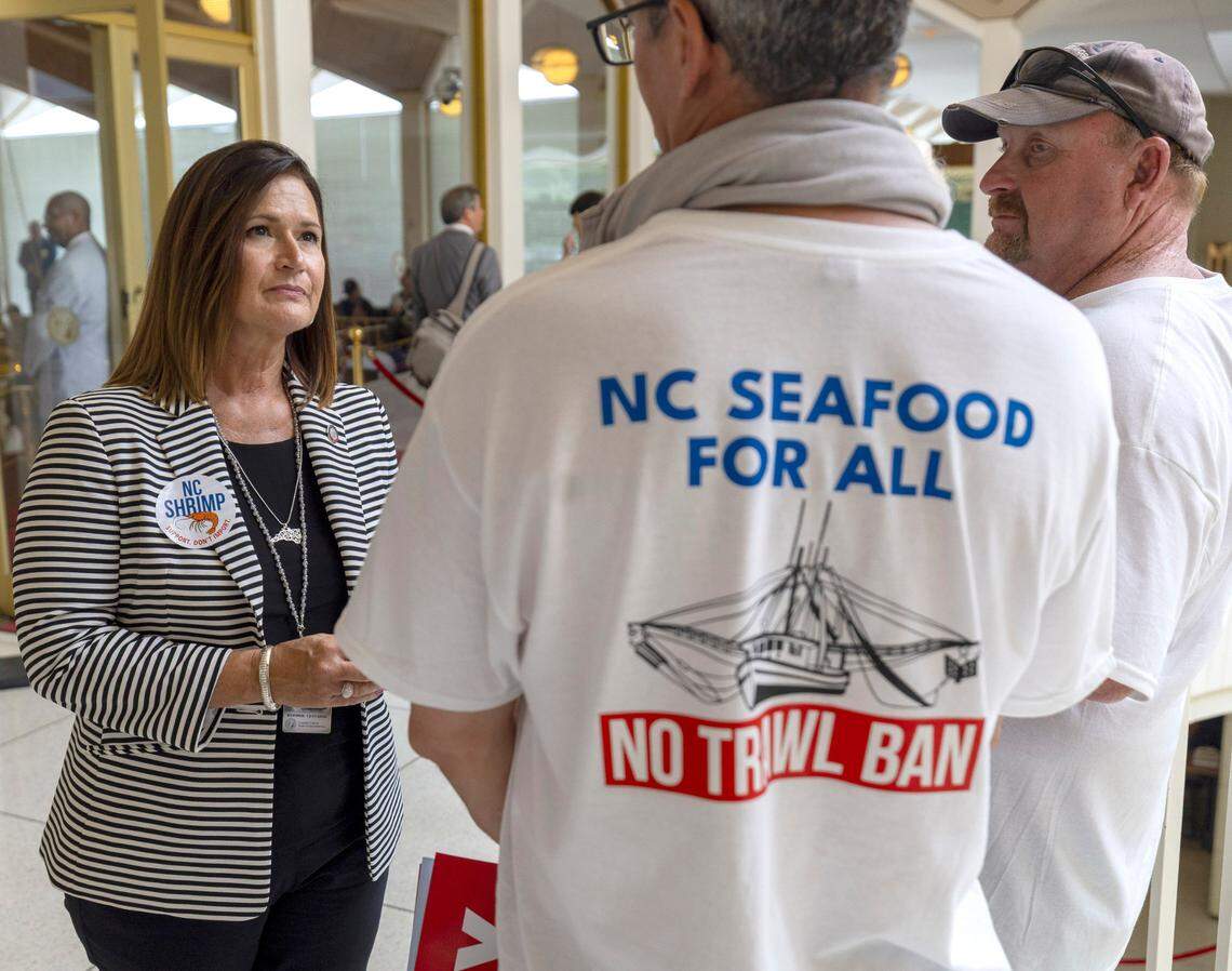 Rep. Celeste Cairns, who represents Carteret County, talks with shrimpers Larry Kellum Jr. and Kenny Rustic outside the House chamber on Tuesday, June 24, 2025 in Raleigh, N.C. Kellum and Rustic were among the hundreds of fishing industry employees working to stop HB 442, which would ban shrimp trawling in all inshore fishing waters and within one-half mile of the shoreline.