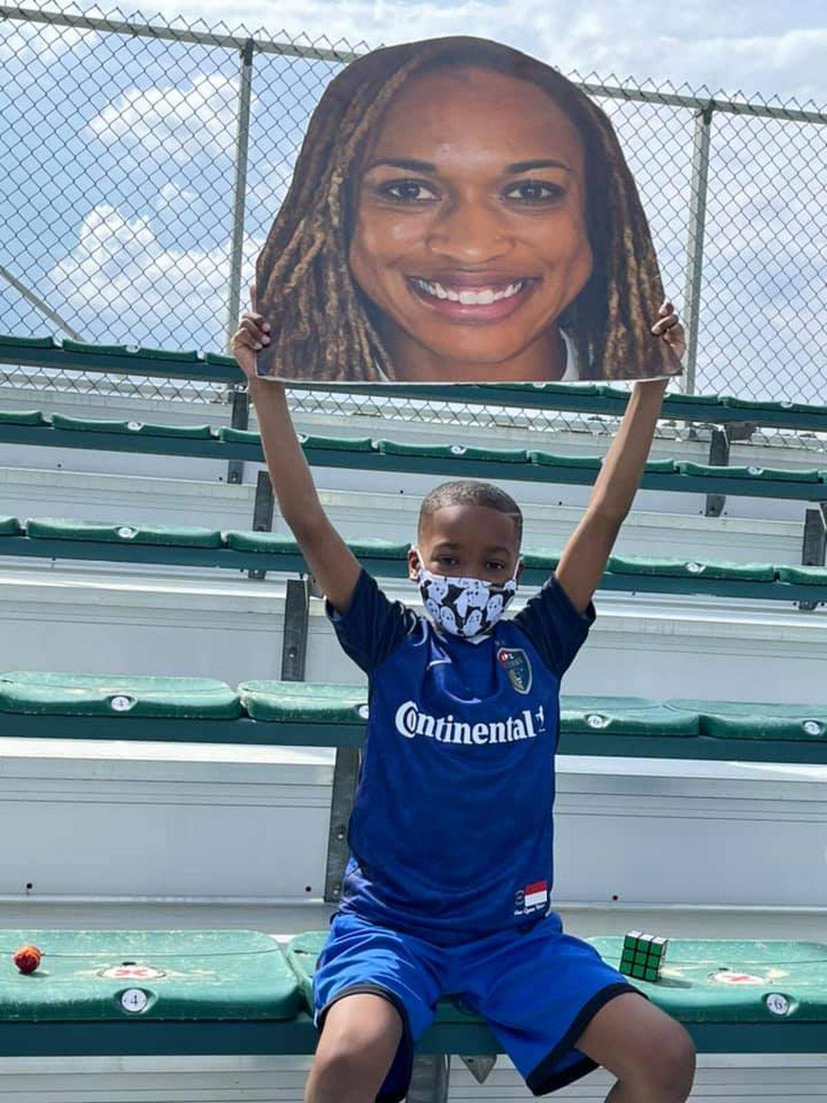 Jeremiah Stuart holds up a picture of his mother, Jessica McDonald, at a North Carolina Courage game. McDonald was a star for the Courage in the NWSL before being traded to Louisville this offseason.