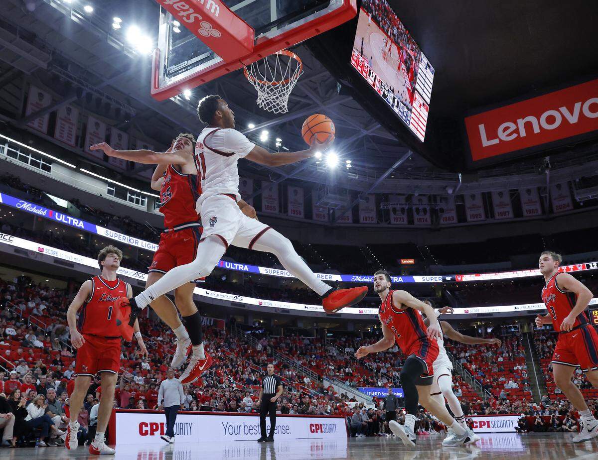 N.C. State’s Quadir Copeland drives to the basket past Liberty’s Zach Cleveland during the first half of the Wolfpack’s game on Wednesday, Dec. 10, 2025, at Lenovo Center in Raleigh, N.C. 