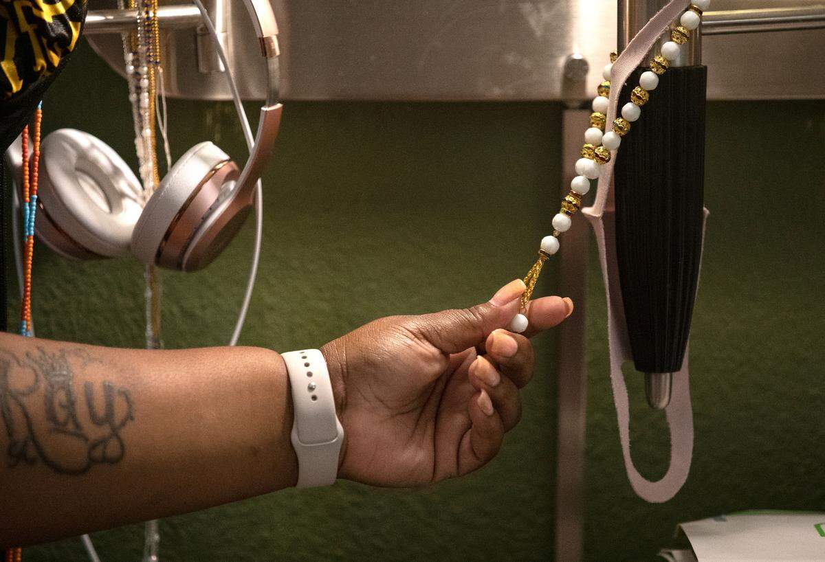LaSherron Geddie touches her prayer beads while sitting in the room of an extended stay hotel in Raleigh, N.C. on Monday, June 27, 2022. Geddie says she also places notecards with positive affirmations around the hotel room and her car to give herself constant reminders of encouragement.