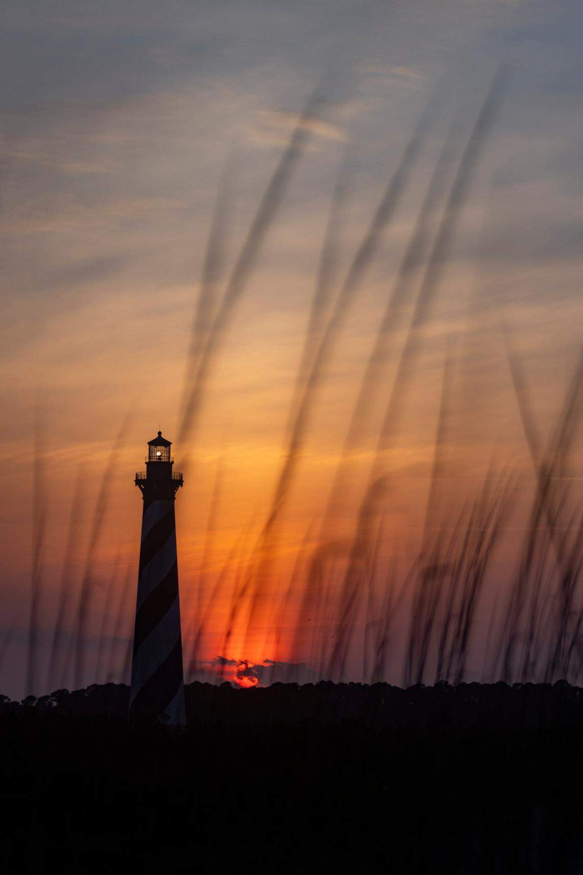 The sun sets behind the Cape Hatteras Light Station in Buxton Thursday, May 19, 2022.