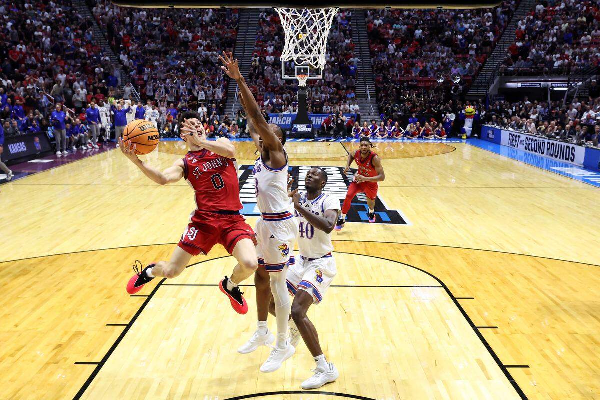 Dylan Darling (0) of St. John's shoots lays the ball in over Kansas’ Elmarko Jackson, center, and Flory Bidunga in the final seconds of the teams’ second round game at the 2026 NCAA Men's Basketball Tournament at Viejas Arena at San Diego State University on March 22, 2026 in San Diego, California.