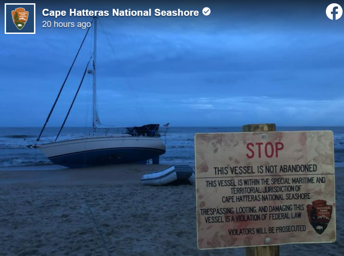 A sign in front of the grounded boat warns against trespassing on or damaging the boat.