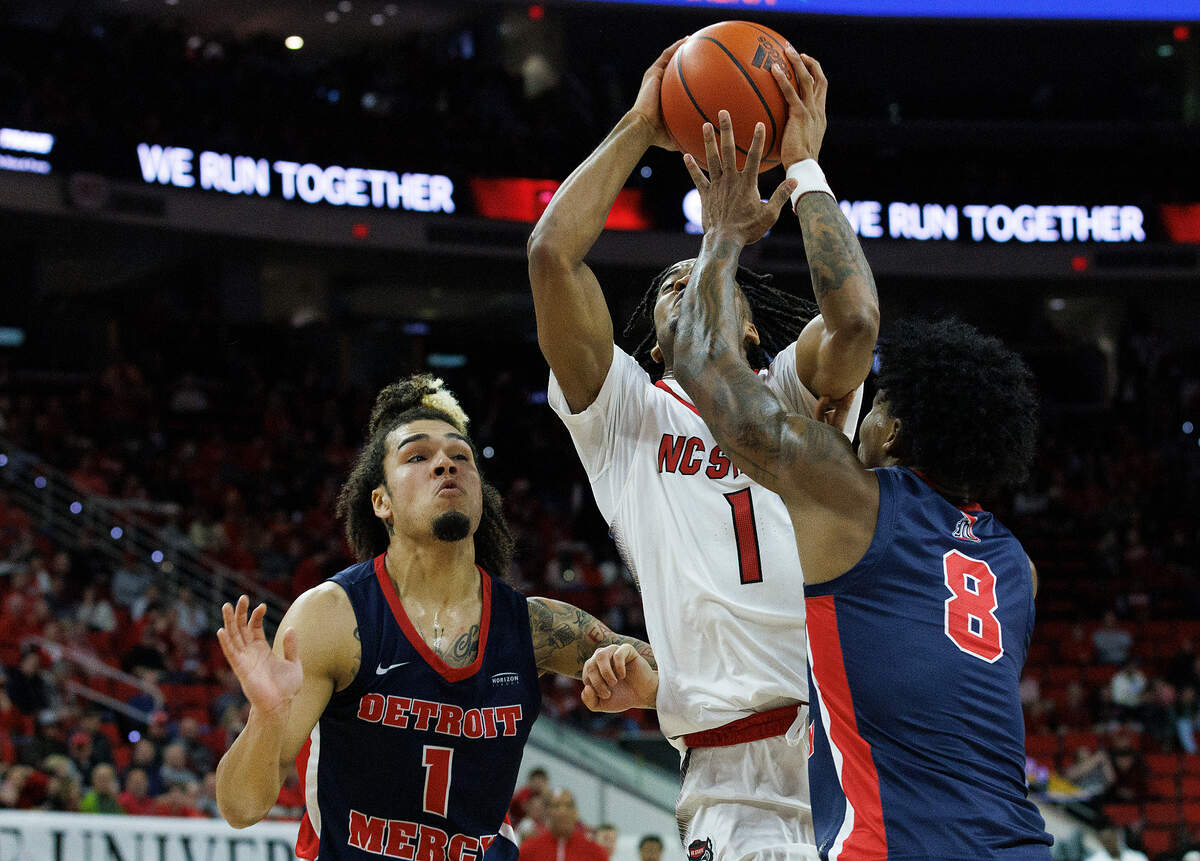 N.C. State’s Jayden Taylor drives to the basket between Detroit’s Mak Manciel and Donovann Toatley during the first half of the Wolfpack’s game on Saturday, Dec. 23, 2023, at PNC Arena in Raleigh, N.C.