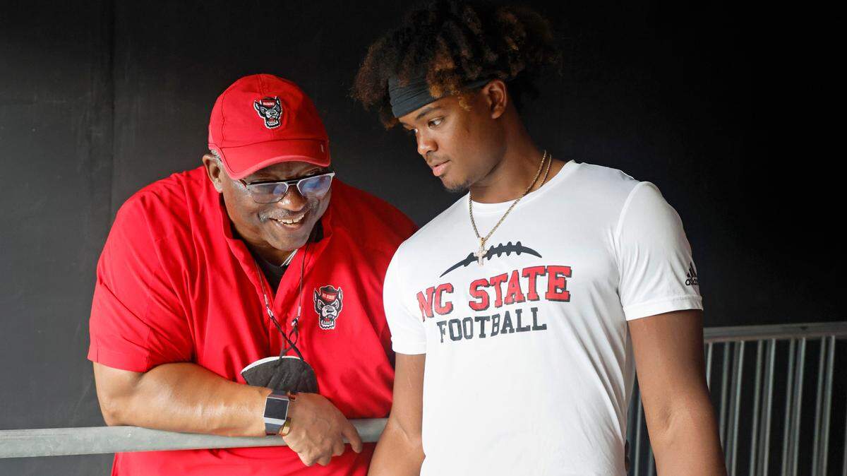 N.C. State’s Ruffin McNeill, special assistant to the head coach, talks with quarterback MJ Morris during the Wolfpack’s Victory Day at Carter-Finley Stadium in Raleigh, N.C., Friday, August 5, 2022. On Victory Day, the Wolfpack partner with GiGi’s Playhouse, giving cognitively and physically impaired children a chance to play football alongside the Pack.