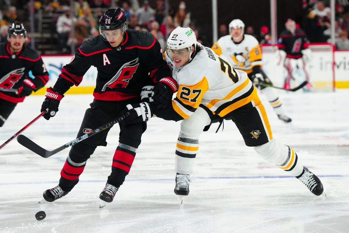 Nov 18, 2023; Raleigh, North Carolina, USA; Carolina Hurricanes center Sebastian Aho (20) tries to control the puck against Pittsburgh Penguins defenseman Ryan Graves (27) during the first period at PNC Arena. Mandatory Credit: James Guillory-USA TODAY Sports