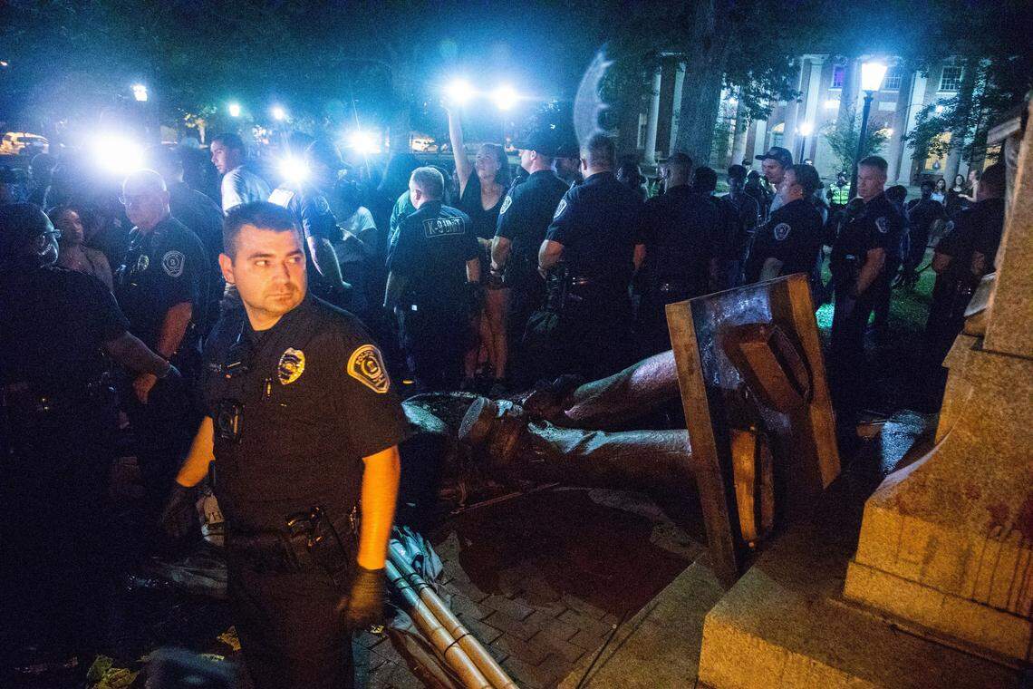 Police surround the toppled remains of a Confederate statue known as Silent Sam on Monday at UNC-Chapel Hill. Demonstrators surrounded and obscured the statue with large banners before toppling it.