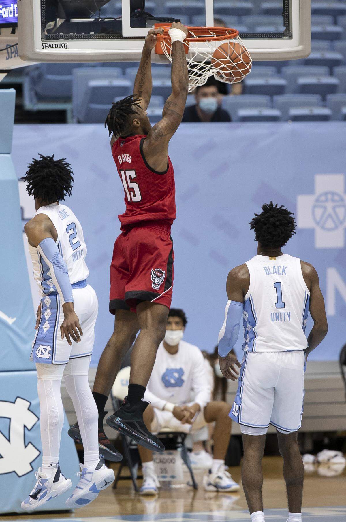 N.C. State’s Manny Bates (15) gets a dunk between North Carolina’s Leaky Black (1) and Caleb Love (2) in the first half on Saturday, January 23, 2021 at the Smith Center in Chapel Hill, NC.