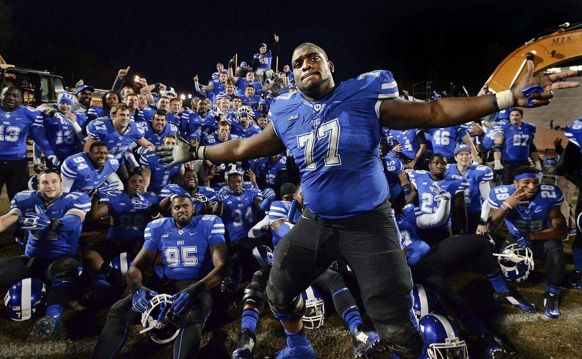 Duke guard Laken Tomlinson (77) photo bombs a group shot as the Blue Devil football team poses with heavy equipment prior to the groundbreaking ceremony after Duke beat Wake Forest 41-21 at Wallace Wade Stadium Saturday, Nov. 29, 2014 in Durham, NC.