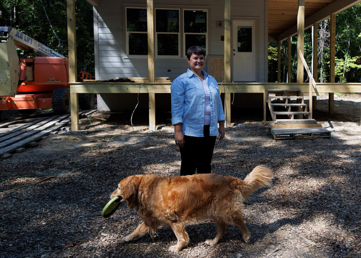 Second Act Farms co-owner Mandy Locke stands alongside Maggie Mae, her 10-year-old Golden Retriever, outside of a home under construction at her farm in Alamance County on Tuesday, Sept. 10, 2024. Locke, along with her husband Alex Granados, is partnering with the North Carolina Center on Actual Innocence to build two homes at the farm that will help support exonerees as they re-integrate into society.