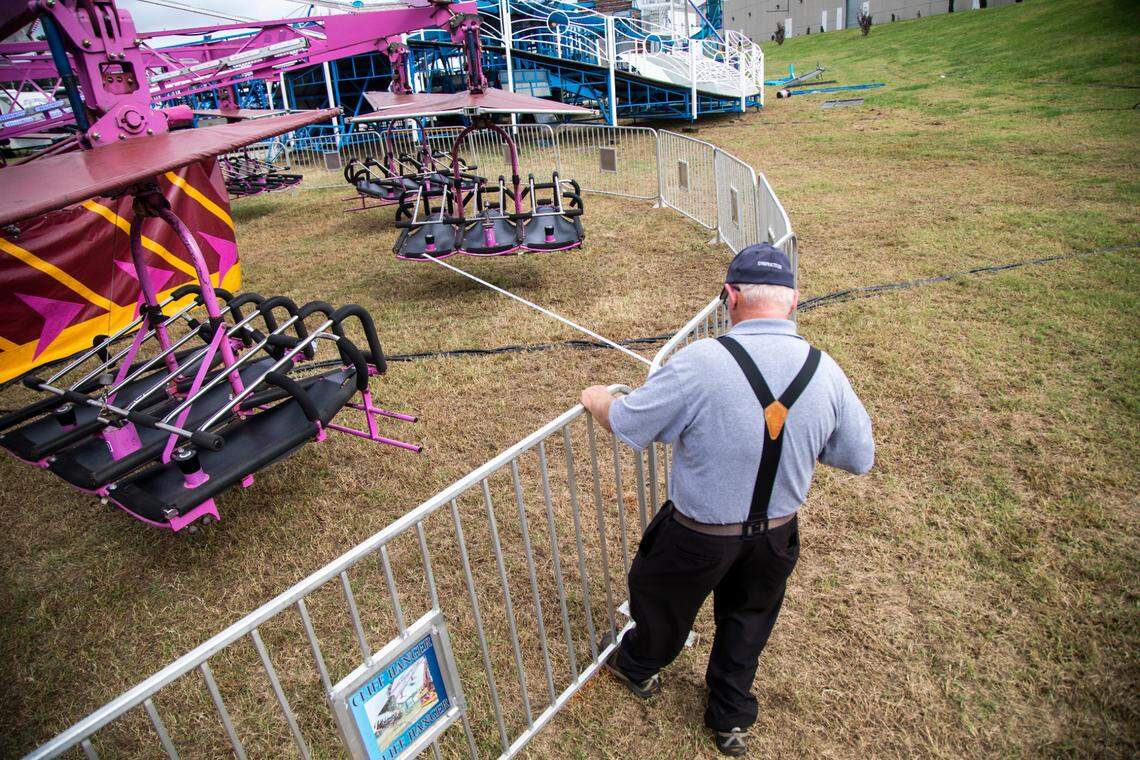 A supervisor with the NC Department of Labor uses a tape measure to make sure guard rails are the proper distance from a ride Tuesday, Oct. 12, 2021 at the NC State Fair in Raleigh.