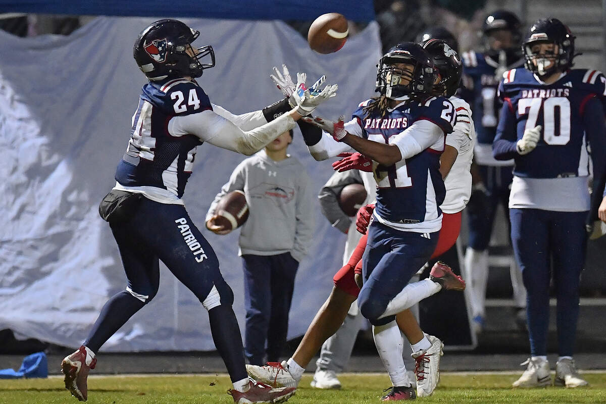 Apex Friendship's Logan Faulring and Bryant Jerome McLean (21) attempt to make the interception against Rolesville's Anthony Roberts (5) late in the second half to force overtime. The Apex Friendship Patriots and the Rolesville Rams met in  the second round of the  NCHSAA 8A Playoff game in Apex, N.C. on November 14, 2025. Rolesville wins 14-7 in overtime.