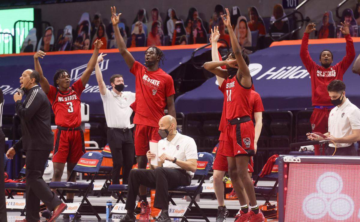 The N.C. State bench reacts to a three-pointer during the Wolfpack’s victory over Virginia in Charlottesville, Va. Wednesday, February 24, 2021.