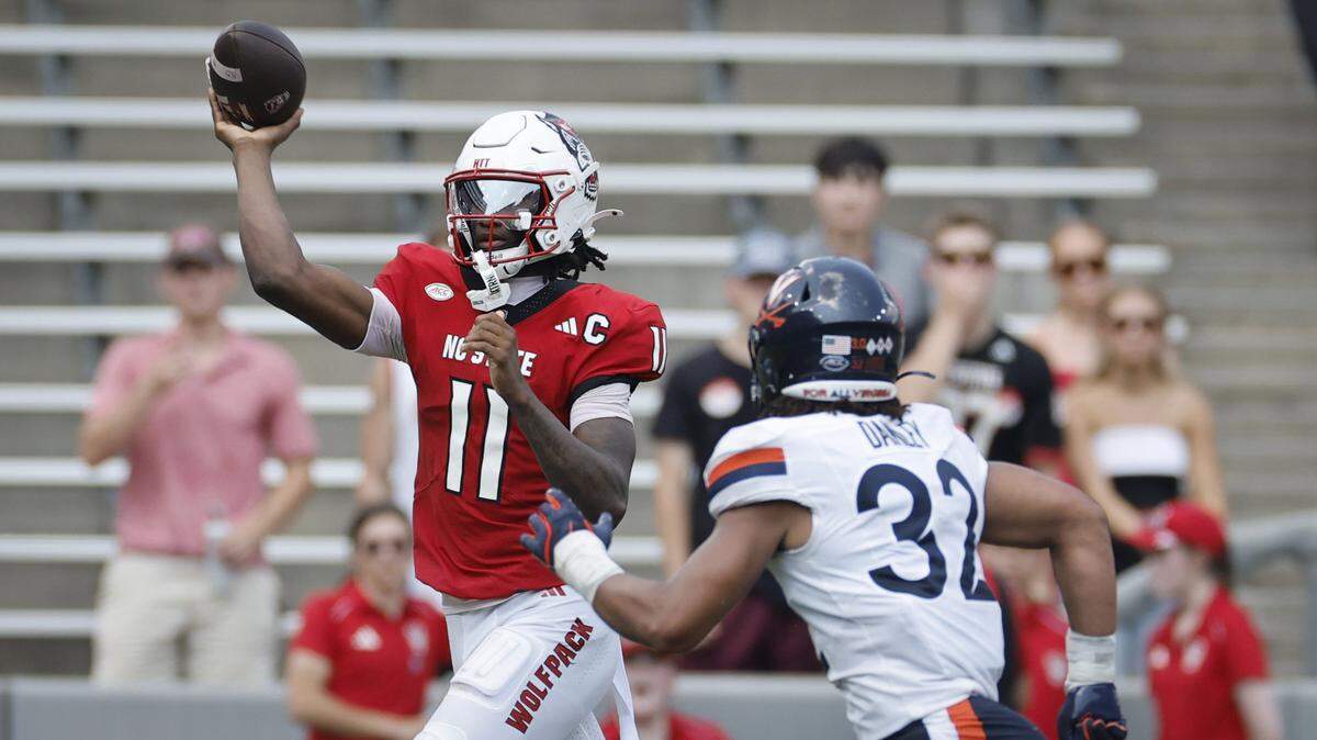 N.C. State quarterback CJ Bailey (11) passes while pursued by Virginia linebacker Landon Danley (32) during the first half of N.C. State’s game against Virginia at Carter-Finley Stadium in Raleigh, N.C., Sat. Sept. 6, 2025.