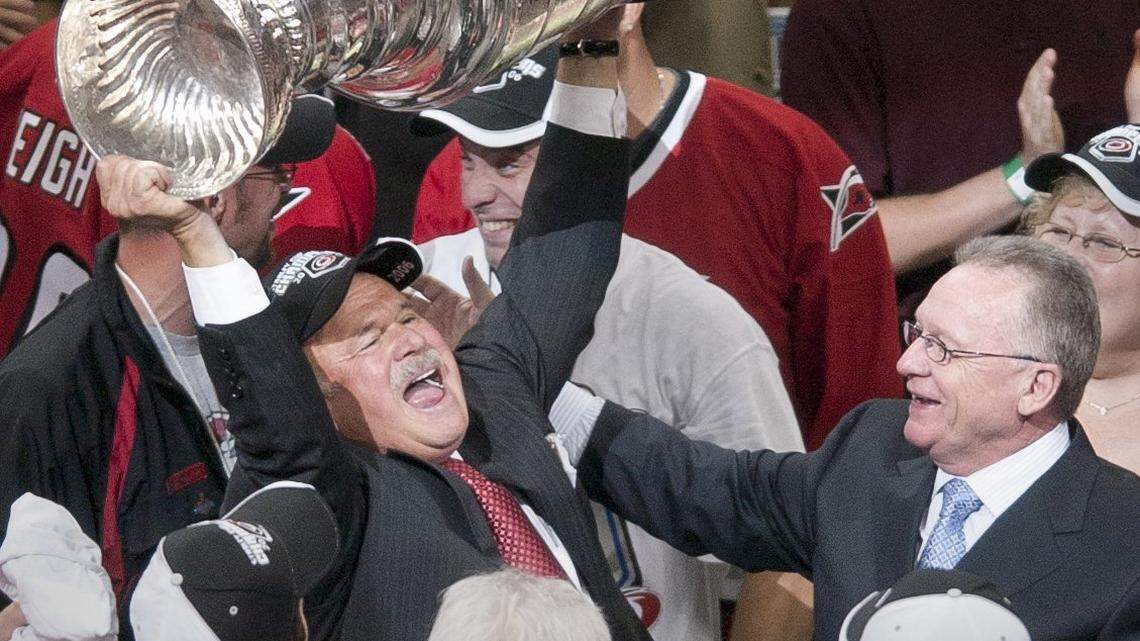 The Carolina Hurricanes team owner Peter Karmanos Jr. , left, hoists the Stanley Cup after his team defeated the Edmonton Oilers 3-1 in Game Seven of the Stanley Cup Finals played in Raleigh on June 19, 2006 as the Canes general manger Jim Rutherford looks on at right.