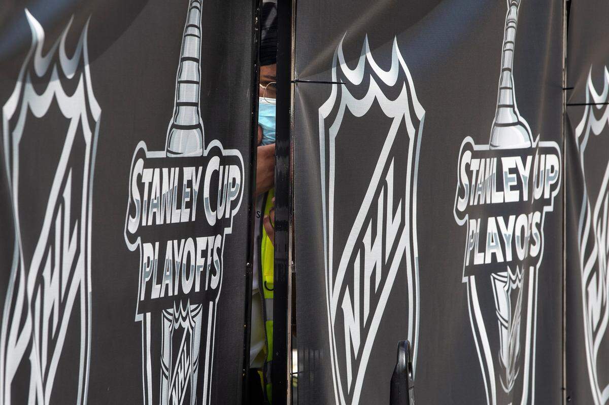 A security guard peers out from behind NHL-branded fencing at the entrance where players arrive at Toronto’s Royal York hotel, which is acting as the “bubble” ahead of the return of the league’s season following disruption due to the COVID-19 pandemic, Sunday, July 26, 2020. (Chris Young/The Canadian Press via AP)