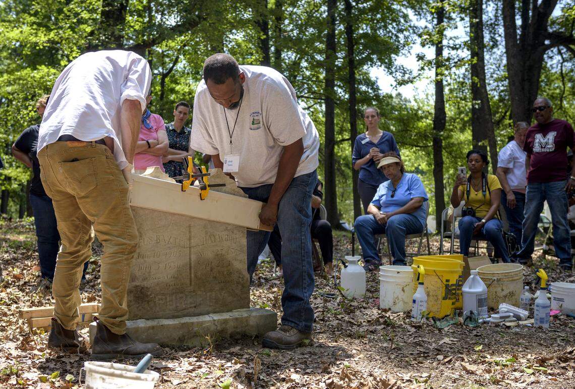 Ron Bartholomew and Wayne Tabron help re-erect and restore a headstone at the Geer Cemetery in Durham, NC, on June 22, 2019.
