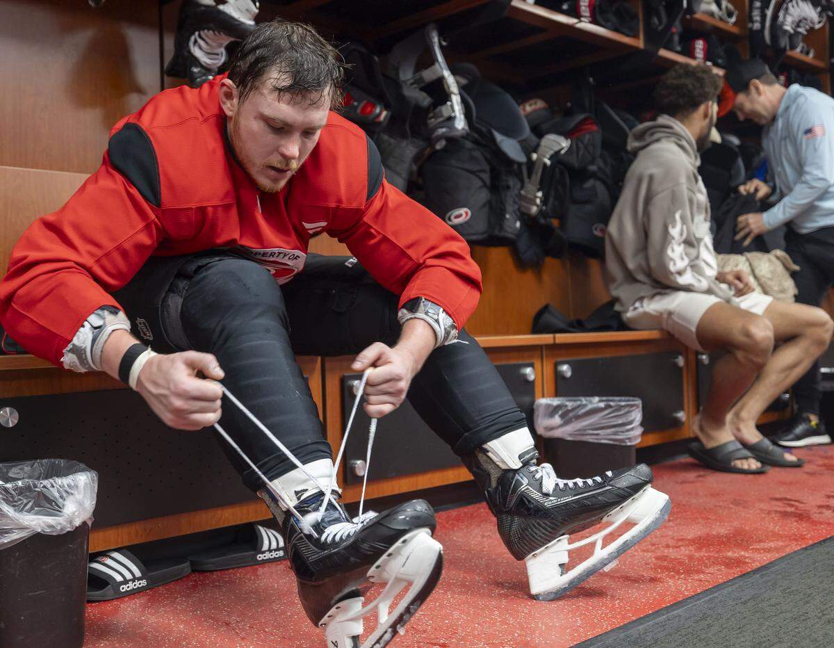 Carolina Hurricanes defenseman Alexander Nikishin (21) removes his skates in the locker room following practice on Friday, May 15, 2026 at Lenovo Center in Raleigh, N.C.