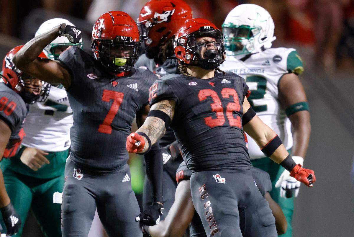 N.C. State linebacker Drake Thomas (32) celebrates a stop during the first half of N.C. State’s game against USF at Carter-Finley Stadium in Raleigh, N.C., Thursday, Sept. 2, 2021. N.C. State cornerback Chris Ingram (7) celebrates with Thomas.