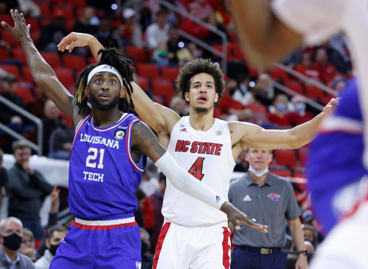 N.C. State’s Jericole Hellems (4) watches his three-pointer go in during the first half of N.C. State’s game against Louisiana Tech at PNC Arena in Raleigh, N.C., Saturday, November 27, 2021. Louisiana Tech’s Exavian Christon (21) also watches.