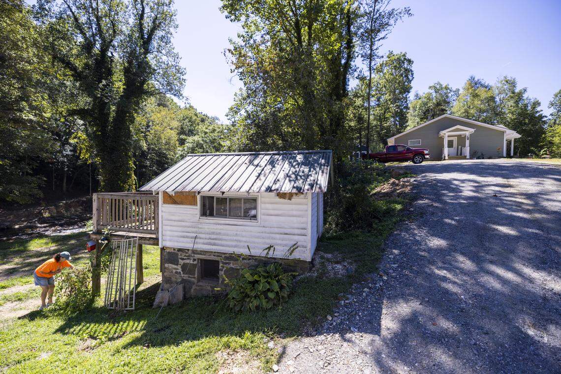 Lisa Thomas picks tomatoes in August outside her shed, from where she watched floodwaters and a landslide destroy her Spruce Pine home last year. Her new home, built on higher ground by Samaritan’s Purse, is visible in the background.