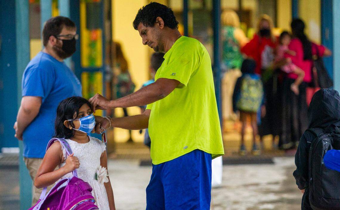 Venkatarao Daggubati helps his daughter Aasya Daggubati adjust her mask as hundreds of students returned to in-person learning as Salem Elementary School in Apex started its year-round school year Thursday, July 8, 2021.