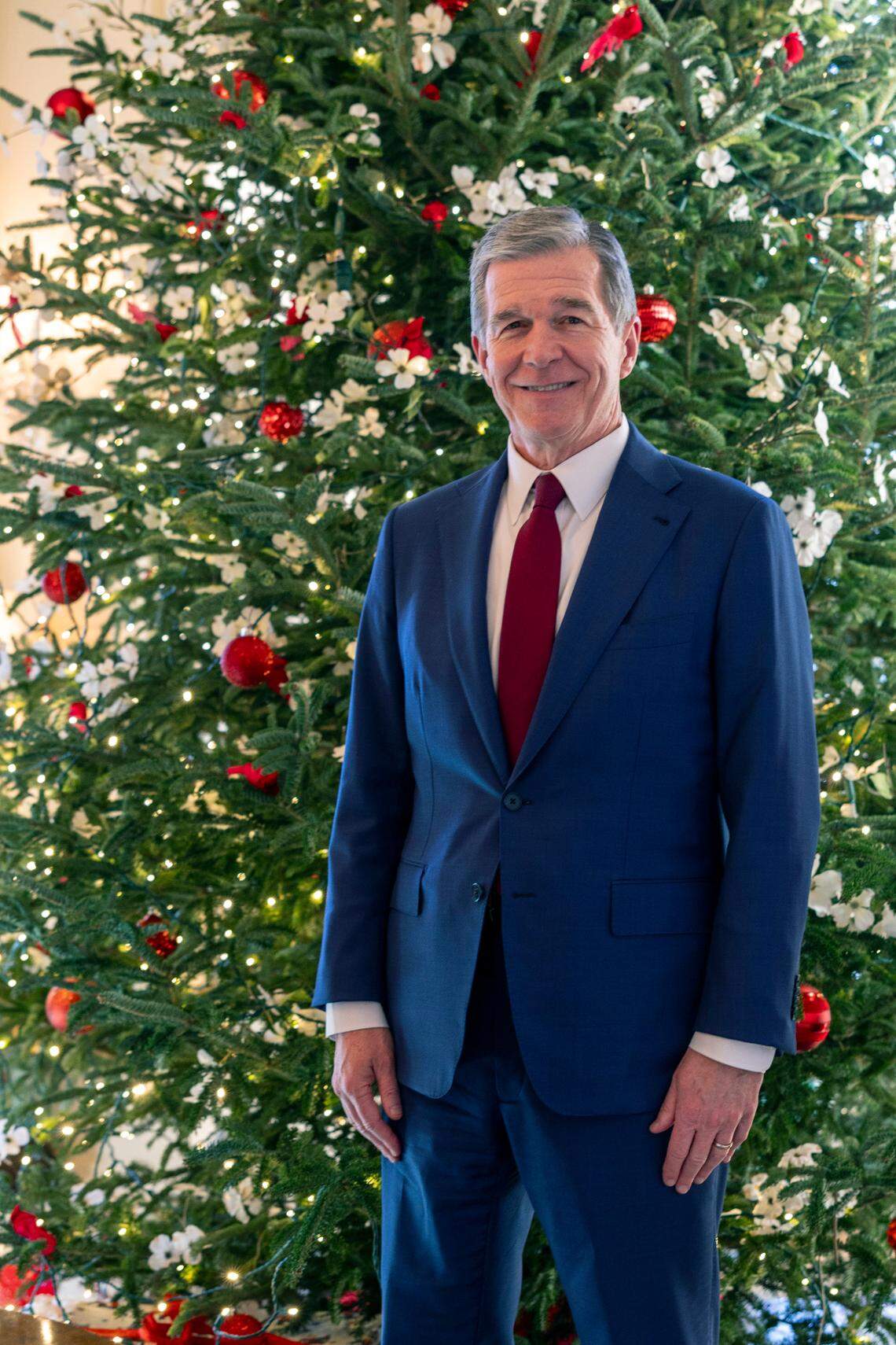 Gov. Roy Cooper stands with one of the Executive Mansion’s Christmas trees Tuesday, Dec. 9, 2023.