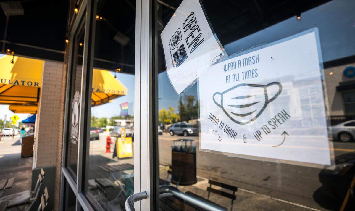 A sign on the door of Hunky Dory, a record store and smoke shop in Durham, on Aug. 11, 2021, instructs patrons to wear a mask inside at all times, including in between sips of beer.