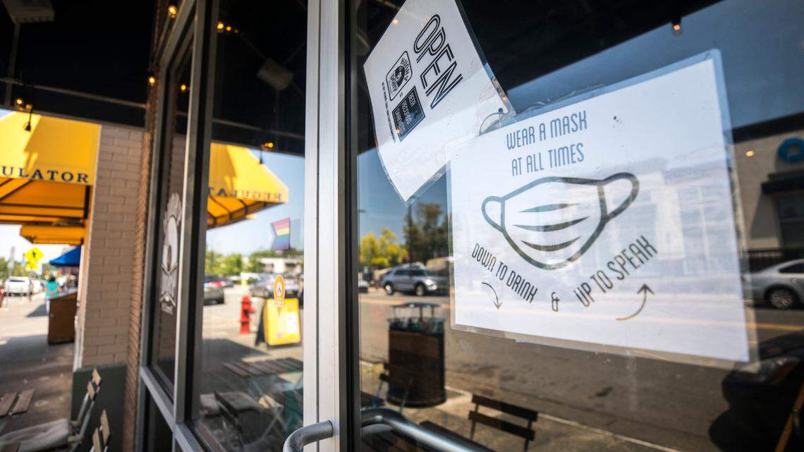 A sign on the door of Hunky Dory, a record store and smoke shop in Durham, N.C., pictured here on Wednesday, Aug. 11, 2021, instructs patrons to wear a mask inside at all times, including in between sips of beer.