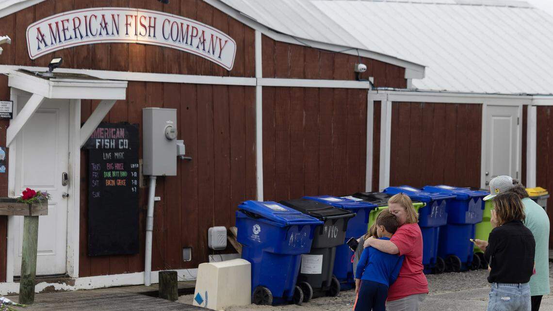 People gather at the scene at American Fish Company in Southport, N.C. Sunday to remember victims in a shooting at the bar the previous evening.  A man in a boat shot from the water, killing three.  