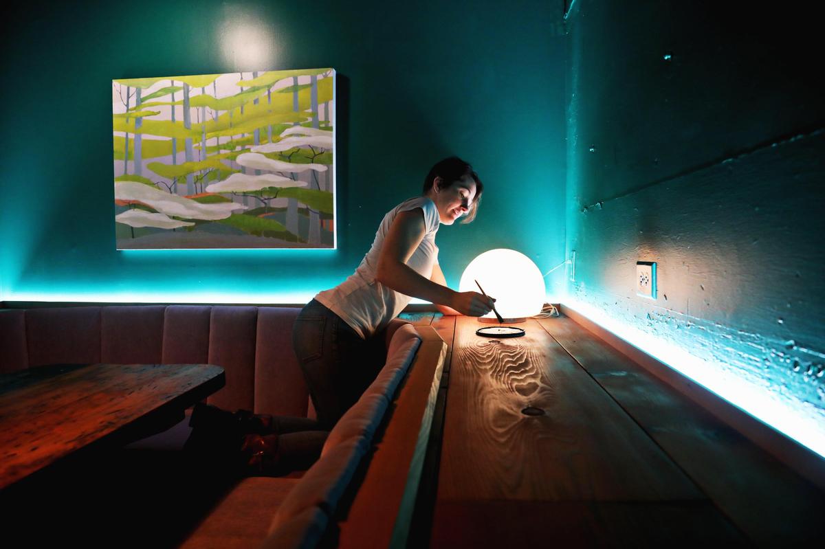 Michelle Vanderwalker finishes up some painting details at Kingfisher Bar on Tuesday, July 30, 2019, in downtown Durham.