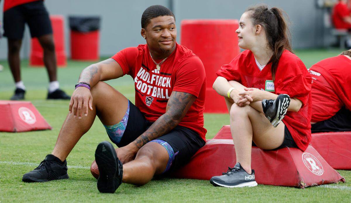 N.C. State’s Demarcus Jones II, left, talks with Anna Merrills during Victory Day at Carter-Finley Stadium in Raleigh, N.C., Friday, August 2, 2024. Victory Day is a partnership between the Wolfpack and GiGi’s Playhouse, a Down Syndrome achievement center in Raleigh. The event provided 52 cognitively and physically impaired people the chance to be football stars for the night.