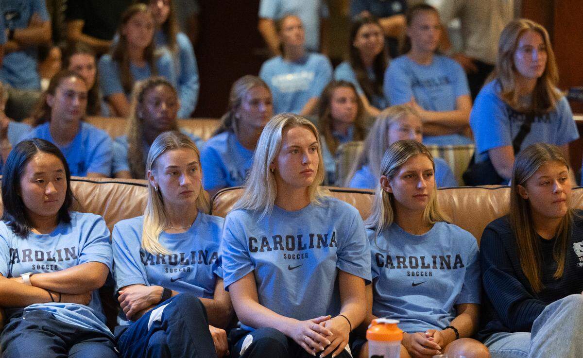 Eden Bretzer, center, a member of the North Carolina women’s soccer team is flanked by her teammates as they listen to coach Anson Dorrance during his public retirement announcement on Monday, August 12, 2024 at the Smith Center in Chapel Hill, N.C. Dorrance retires following 45 seasons and 21 NCAA Championships.