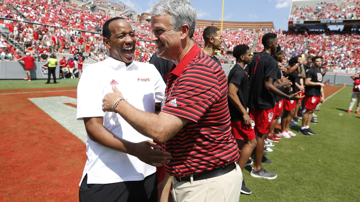 N.C. State basketball head coach Kevin Keatts laughs with athletic director Boo Corrigan after the basketball team was introduced during the first half of N.C. State’s game against Western Carolina at Carter-Finley Stadium in Raleigh, N.C., Saturday, Sept. 7, 2019.