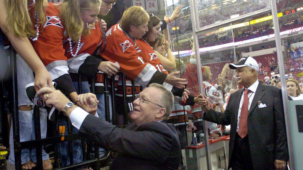 The Carolina Hurricanes general manager Jim Rutherford, left, and owner Pater Karmanos Jr. greet the fans as they come off the ice after hoisting the Stanley Cup in Raleigh on June 19, 2006. The Canes beat the Edmonton Oilers 3-1 in Game Seven of the Stanley Cup finals.