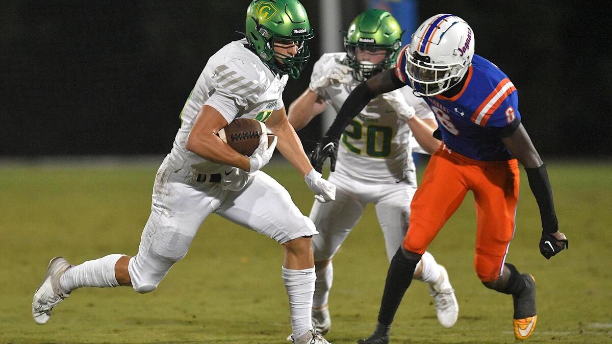 Cardinal Gibbons’ Chey Yardley (14) runs for the first down against Athens Drive’s Caleb Reed (6) during the first half. The Cardinal Gibbons Crusaders and the Athens Drive Jaguars met in a conference football game in Raleigh , N.C. on September 29, 2023.