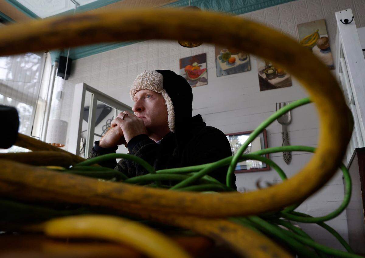 Tom Markey, an employee at Betsy’s Crepes, sits next to power cords meant to supply a generator inside the restaurant on Monday, Dec. 5, 2022, in Southern Pines, N.C.