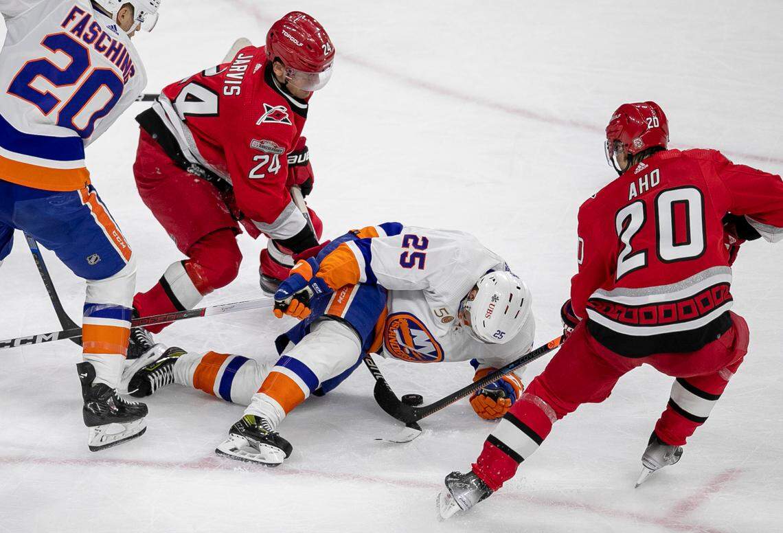 Carolina Hurricanes Seth Jarvis (24) and Sebastian Aho (20) work to get control of the puck from New York Islanders’ Sebastian Aho (25) during the third period in game one of their Stanley Cup playoff series on Monday, April 17, 2023 at PNC Arena in Raleigh, N.C.