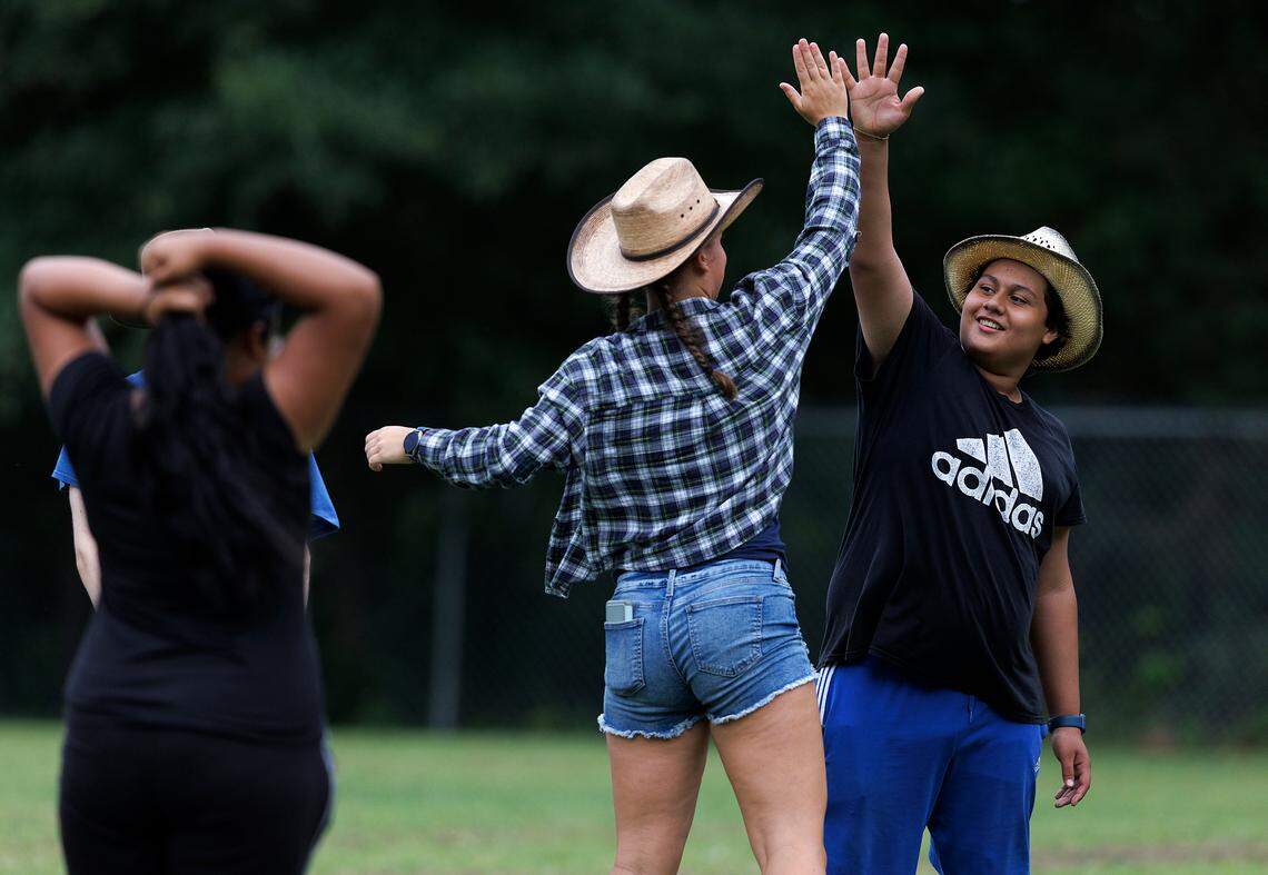 Junior Drum Major Layla Vaughn, center, gives a high-five to freshman Elliot Rivas prior to a performance for parents and families during the final day of marching band camp at Jordan High School on Friday, August 2, 2024, in Durham, N.C.