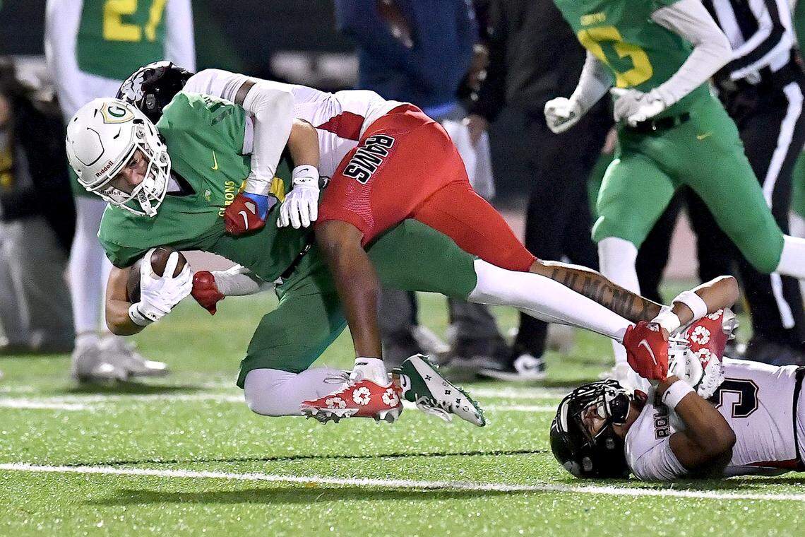Rolesville’s Marion Turner (8) and Zavion Griffin-Haynes (9) tackle Cardinal Gibbons wide receiver Brayden Karras (9) during the first half. The Rolesville Rams and the Cardinal Gibbons Crusaders met in the East Regional Final of the NCHSAA 4A football playoffs in Raleigh, N.C. on December 13, 2024.