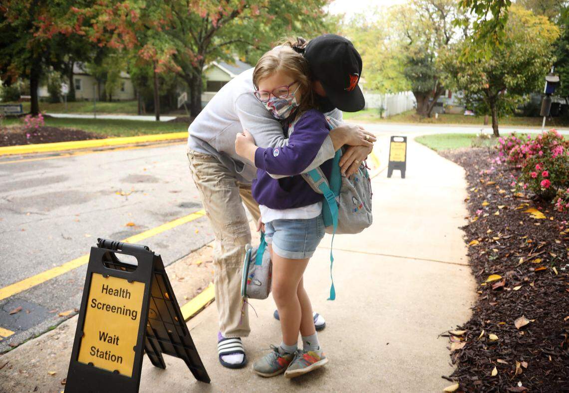 Eloise Marchant, gets a hug from her dad, Enoch, at the health screening wait station outside of Hunter Elementary School in Raleigh on Monday, October 26, 2020, on the first day back in school for some Wake students.