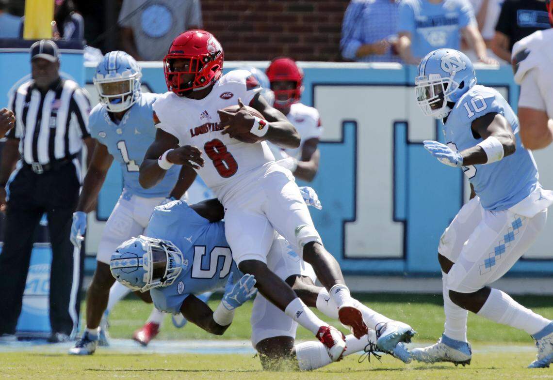 Louisville's Lamar Jackson (8) runs against UNC's Myles Dorn (1), Patrice Rene (5) and Andre Smith (10) during  the first quarter in a game between UNC and Louisville at Kenan Stadium in Chapel Hill on Sept. 9, 2017. 