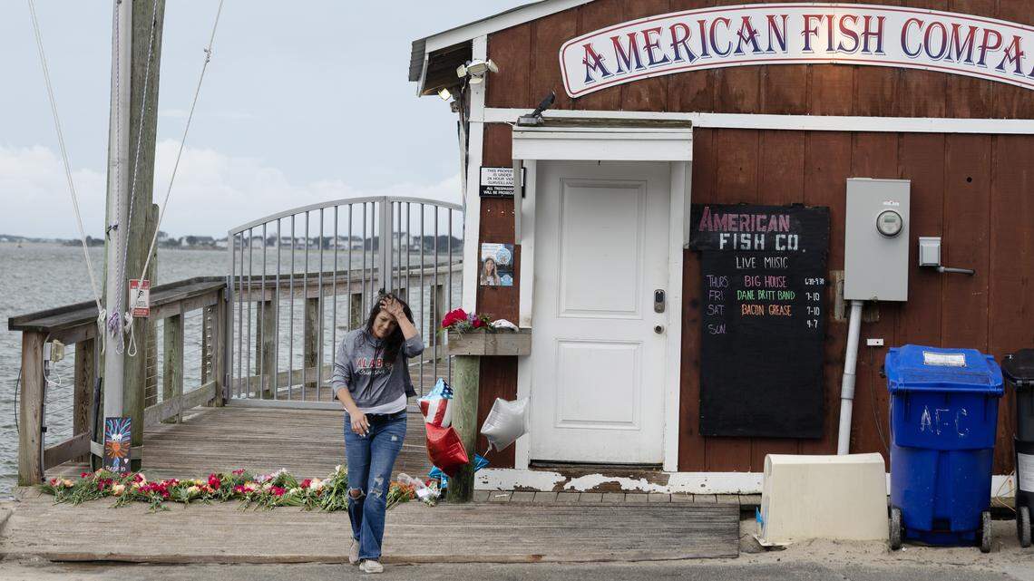 A woman walks away after placing balloons at a memorial for victims of a shooting at the American Fish Company in Southport, N.C., Sunday afternoon, Sept. 28, 2025.  A man in a boat shot into the popular nightspot along the water Saturday night, killing three people.  