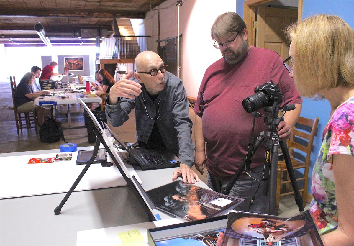 Photographer Burk Uzzle, gesturing, explains the circumstances under which a particular photo from his collection was taken to Kohler Foundation archivists Dan Smith and Susan Kelly. The foundation is moving the archive from Wilson to UNC.