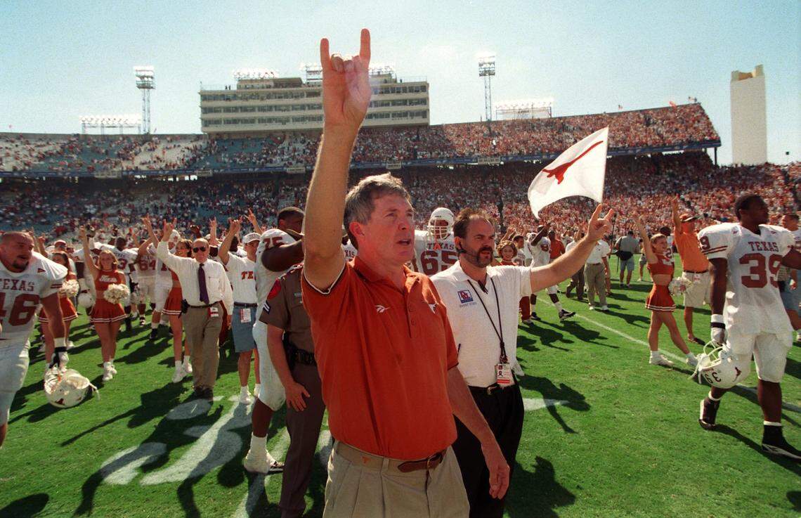 Texas coach Mack Brown flashes the Hook ‘Em Horns” sign as coaches, players and cheerleaders sing the alma mater following their win over Oklahoma.