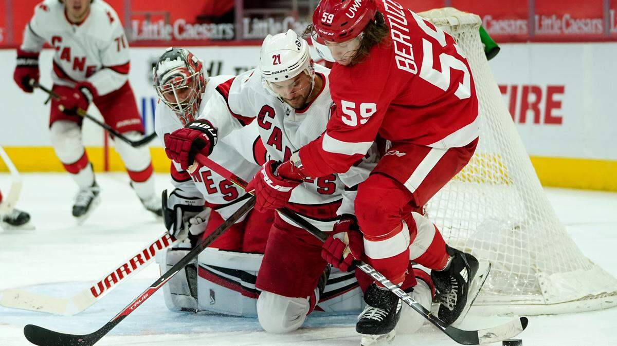 Carolina Hurricanes right wing Nino Niederreiter (21) defends Detroit Red Wings left wing Tyler Bertuzzi (59) in front of goaltender Petr Mrazek (34)in the second period of an NHL hockey game Saturday, Jan. 16, 2021, in Detroit. (AP Photo/Paul Sancya)